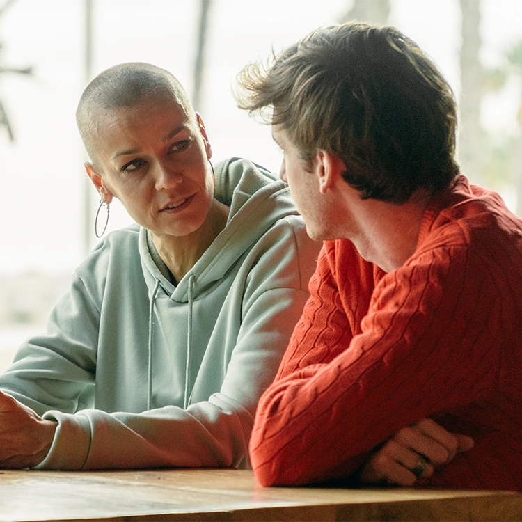 Woman and teenaged boy talking while seated at a table