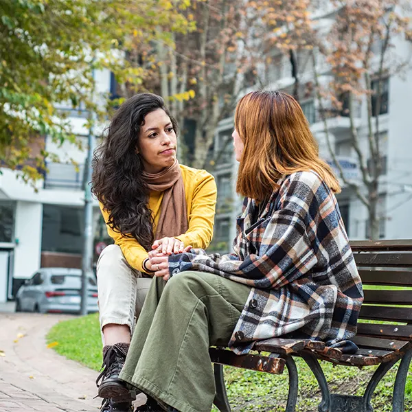Two women chatting while sitting on a park bench