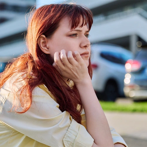 Young woman appears deep in thought while sitting outside