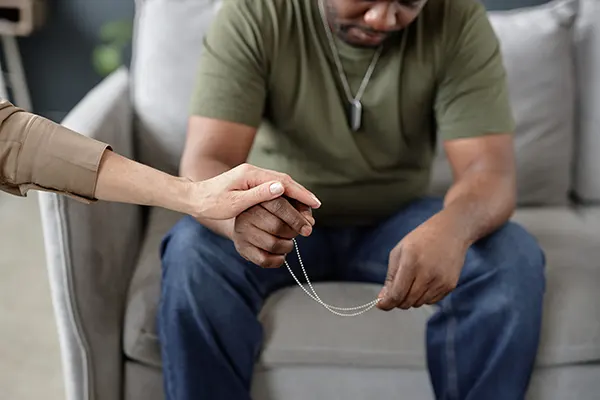 Woman holding a male veterans hand to comfort him on the sofa